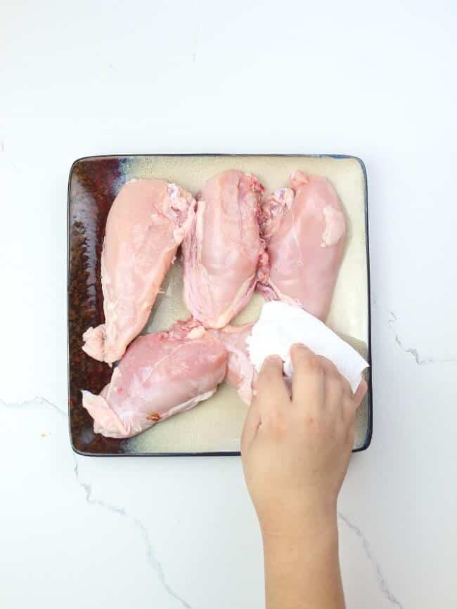 Pat drying chicken using kitchen towel