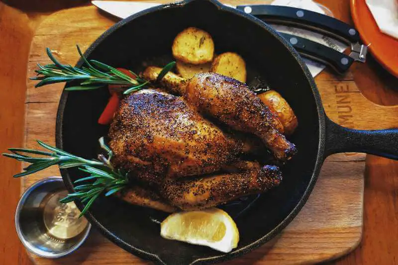 roast chicken on pan with lemon and herbs