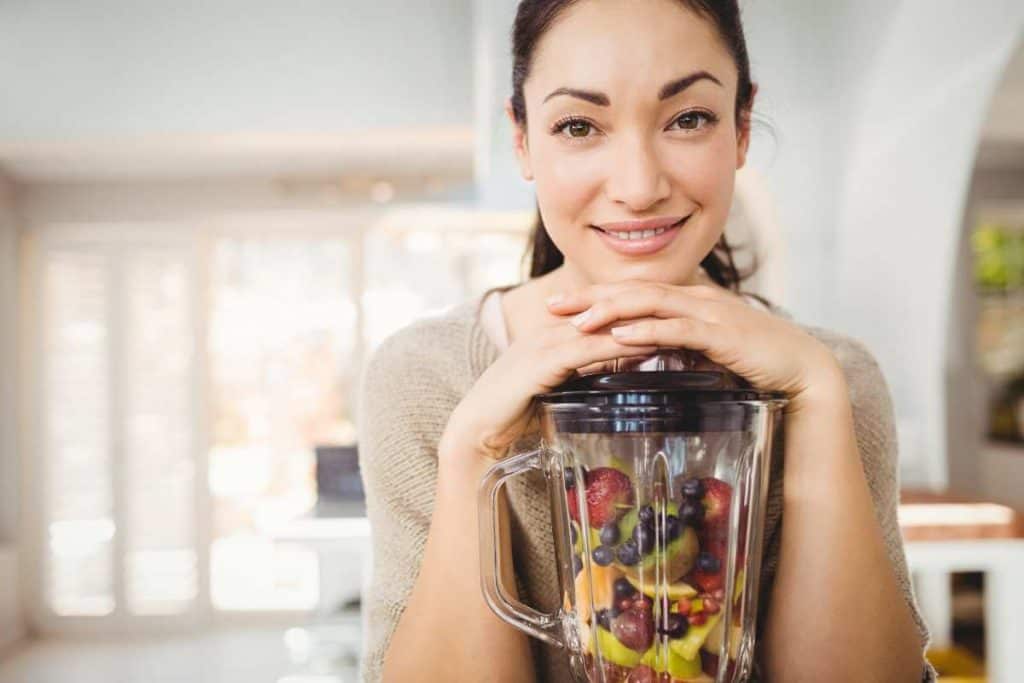 woman with blender containing mixed fruits