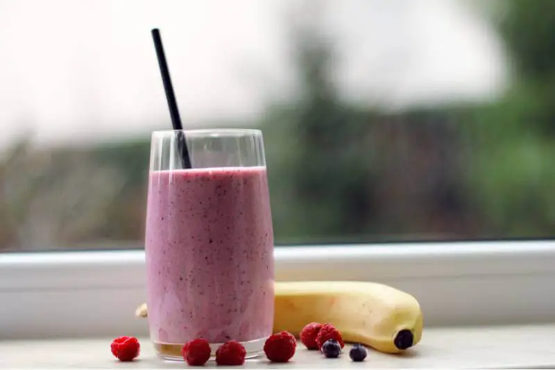 glass of berry banana smoothie with straw
