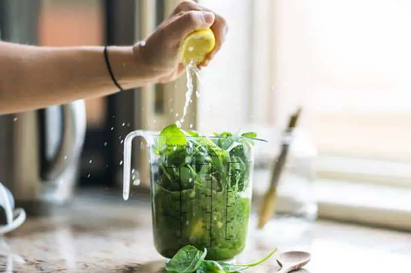 squeezing lemon on greens to make smoothie