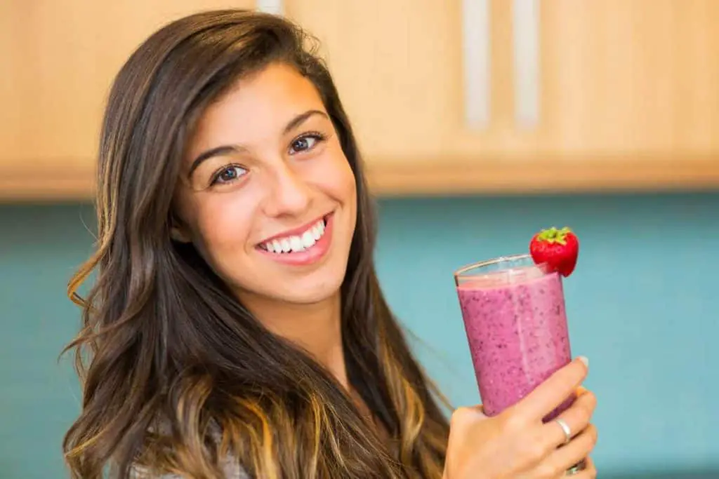 smiling woman holding a glass of smoothie