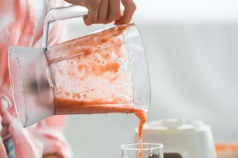 pouring pink smoothie into glass