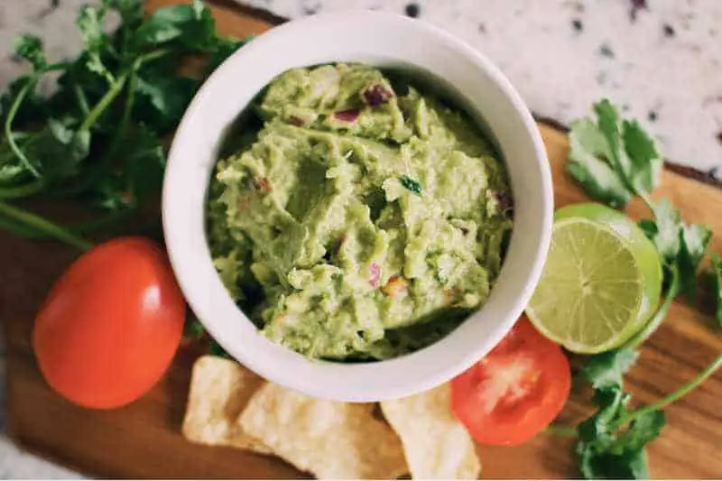 herbs with guacamole in white bowl