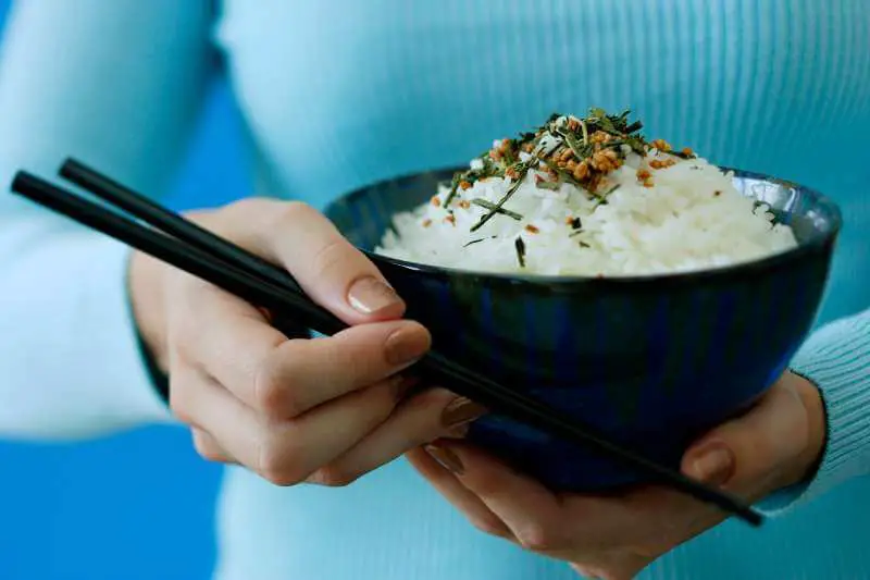 holding a bowl of rice and chopsticks