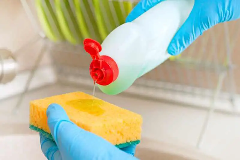 pouring dish soap on sponge