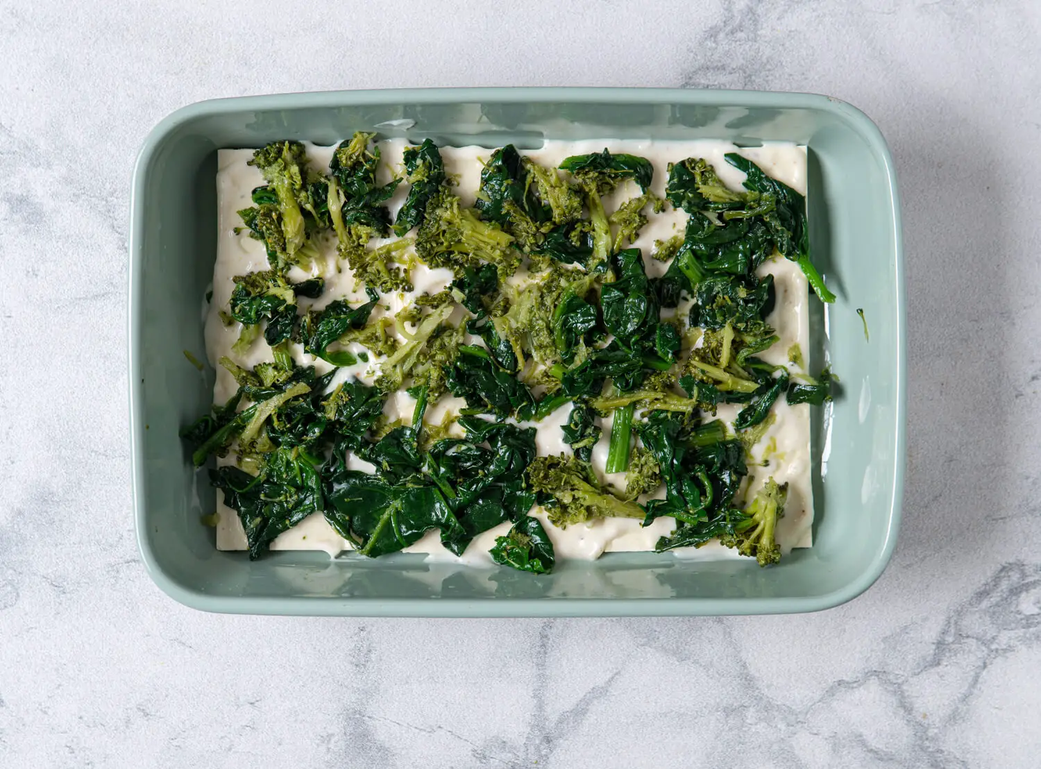 Bechamel sauce, spinach-broccoli mixture, ricotta, and mozzarella go on top of the noodles.