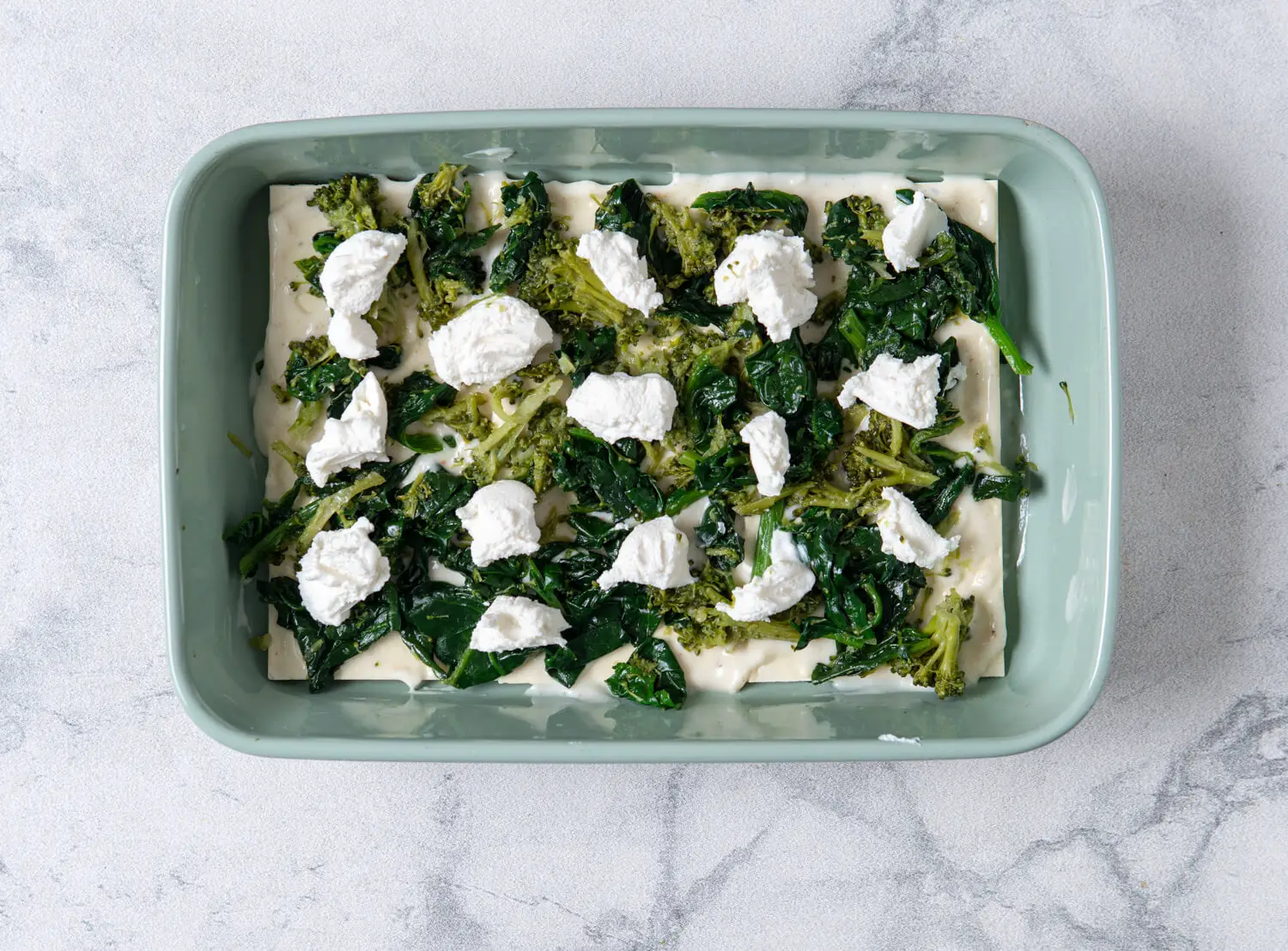 Bechamel sauce, spinach-broccoli mixture, ricotta, and mozzarella go on top of the noodles.