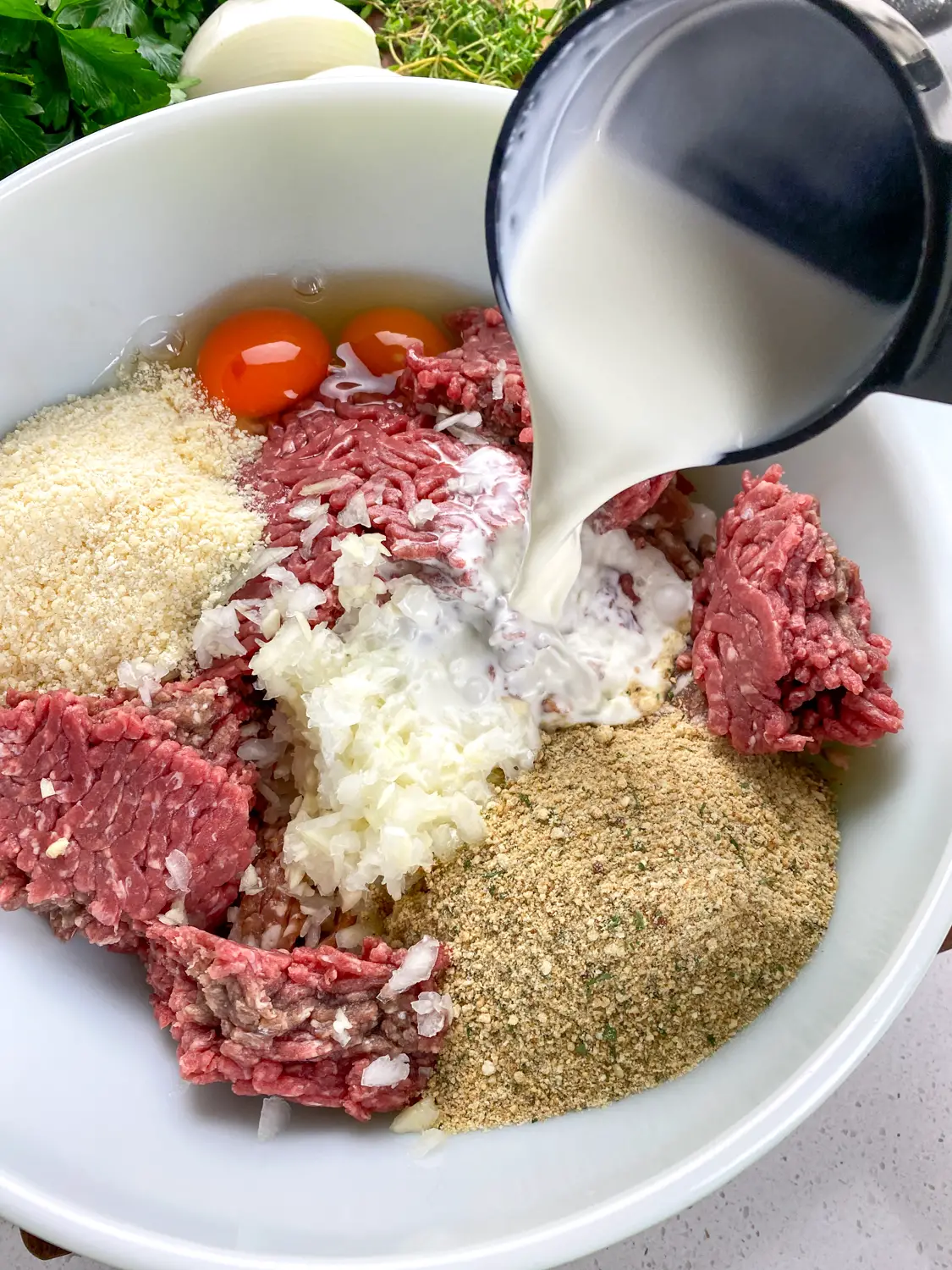 In a large mixing basin, combine the meat, pork, onion, garlic, breadcrumbs, Parmesan cheese, eggs, and whole milk
