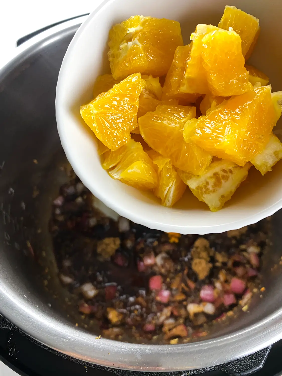 Fill the Instant Pot™ with the brown sugar, orange zest, orange pieces, and cherries.